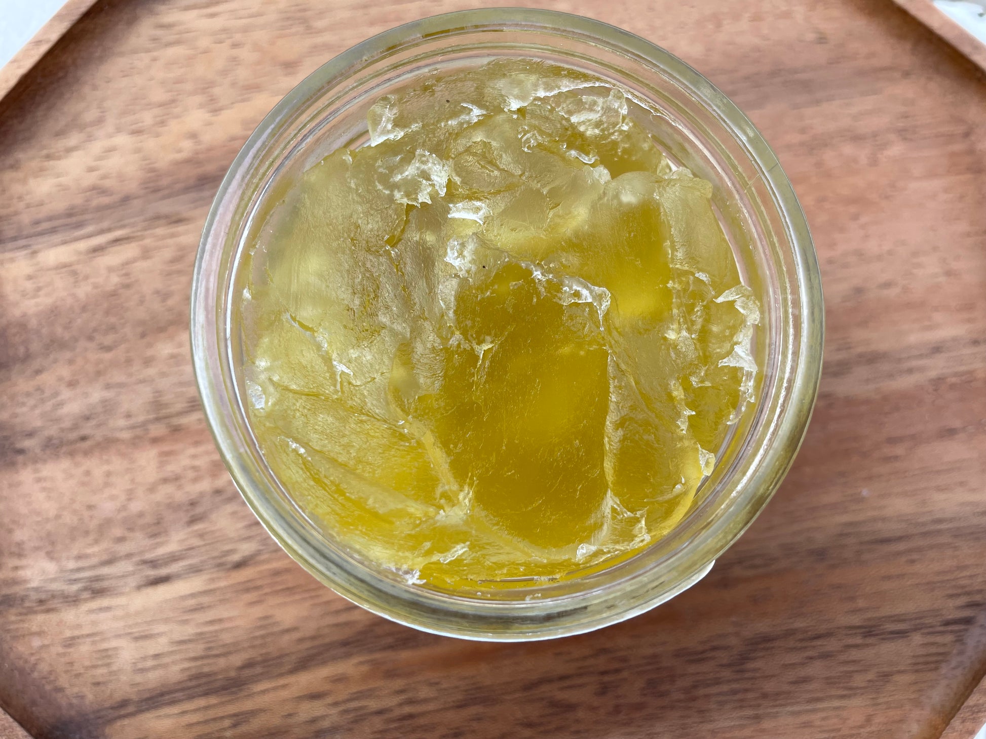 Clear jar pictured from above with a yellow gel inside on a wooden surface.