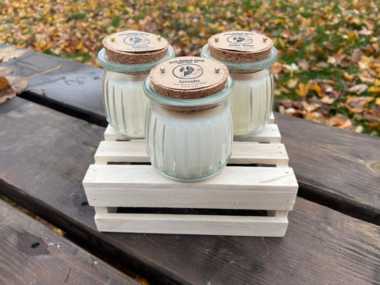 Set of three scented candles in glass jars with cork lids on a wooden crate, featuring lavender and coffee scents.
