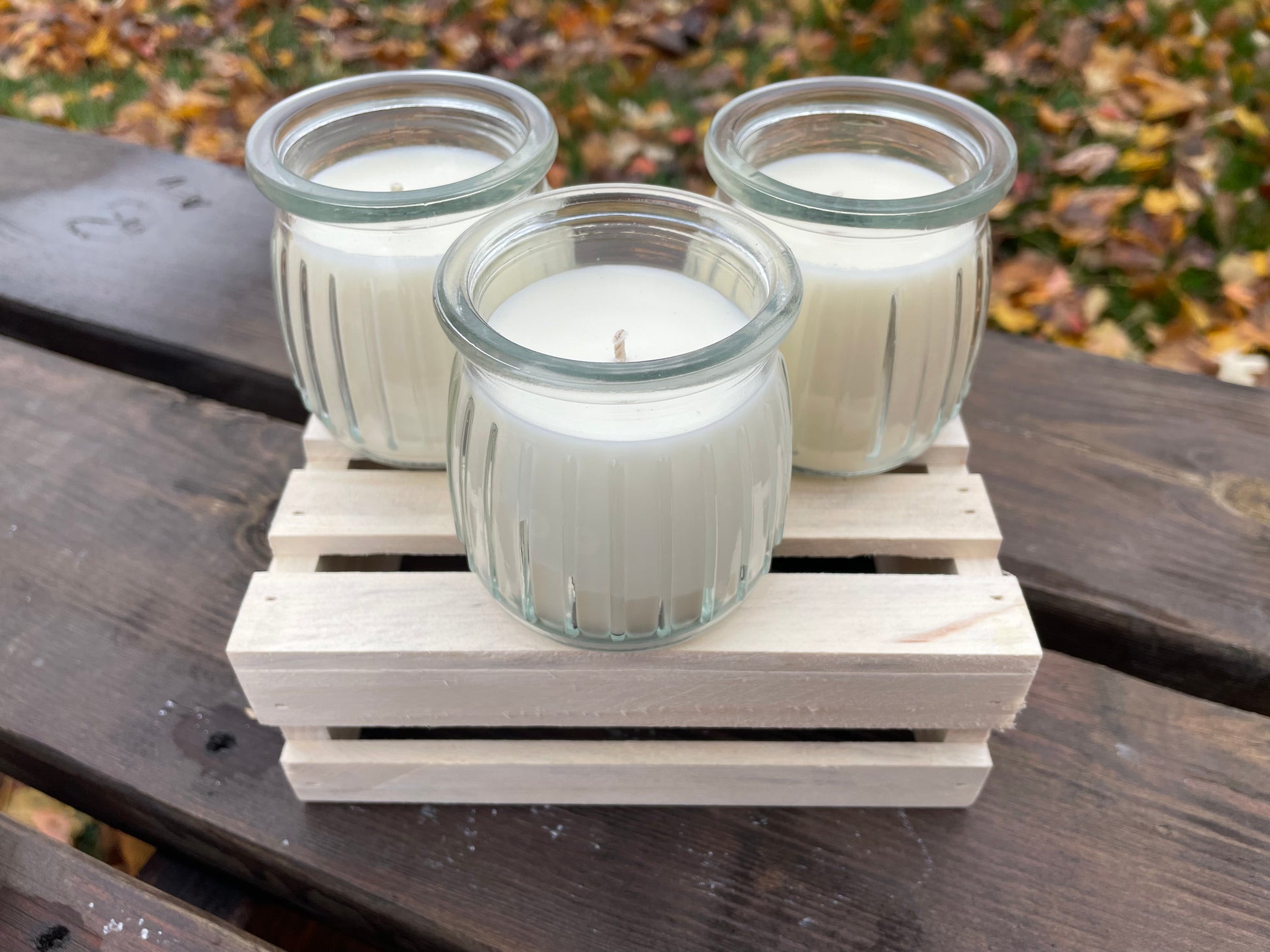 Set of three white sou candles in glass jars on a wooden tray, perfect for home decor.